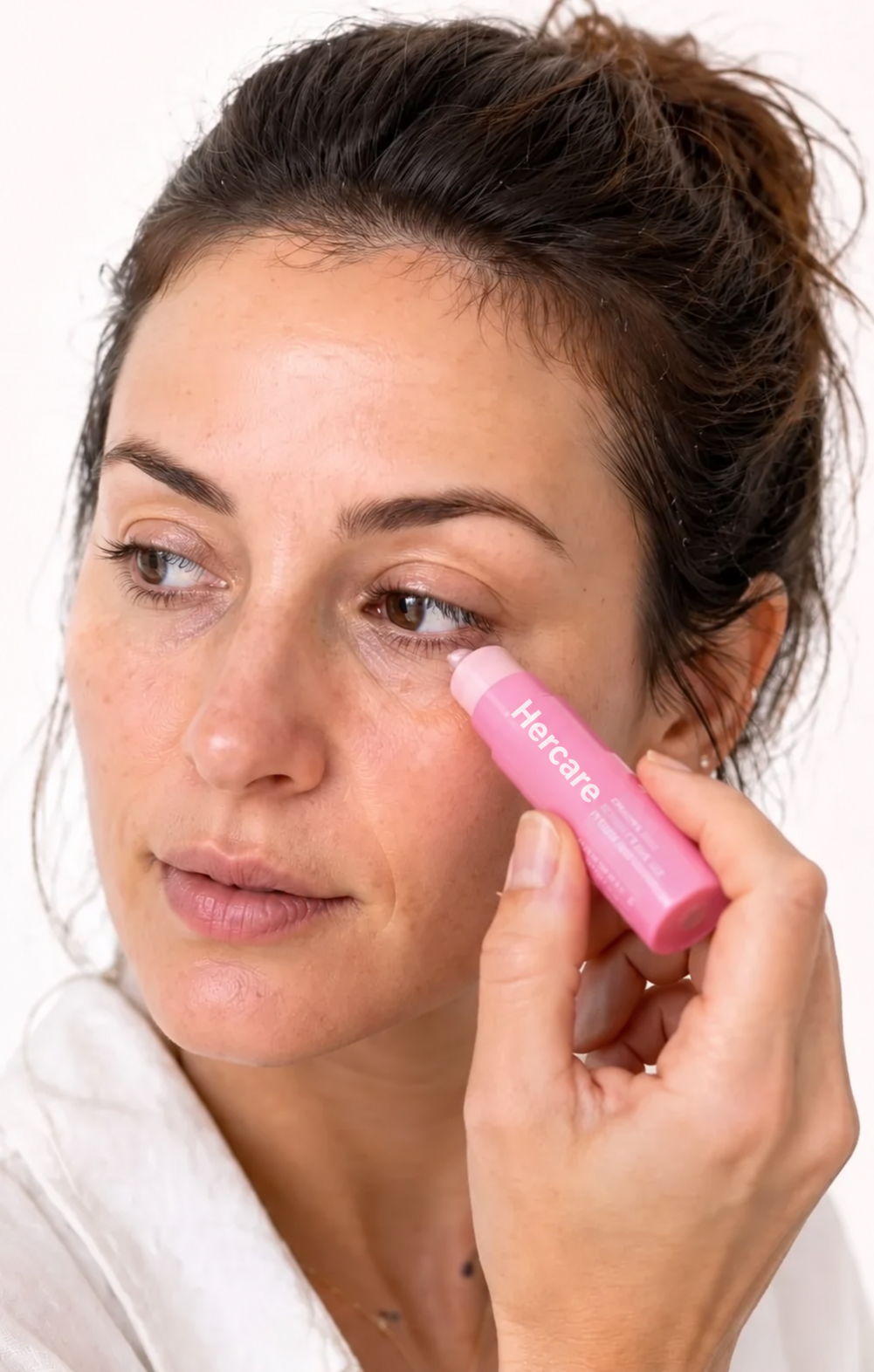 Woman applying Hercare pink balm beneath her eye